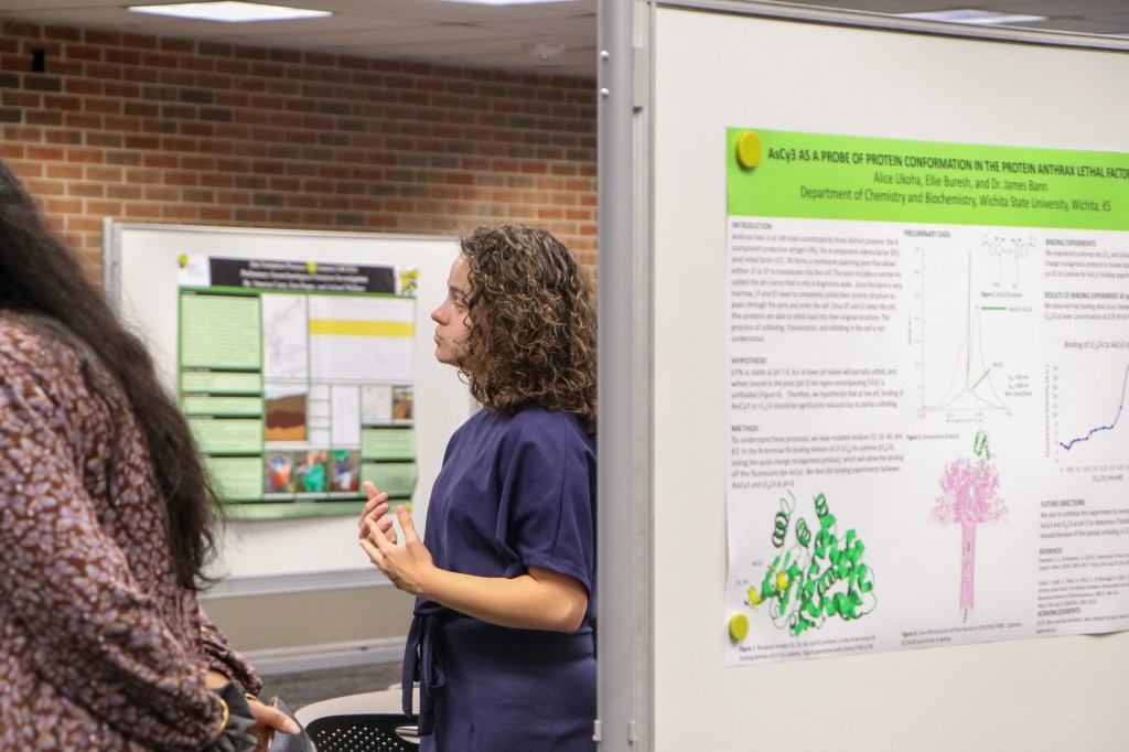 Attendees reviewing and discussing a research poster presentation displayed on an exhibit board.